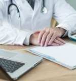 Doctor con manos en el escritorio